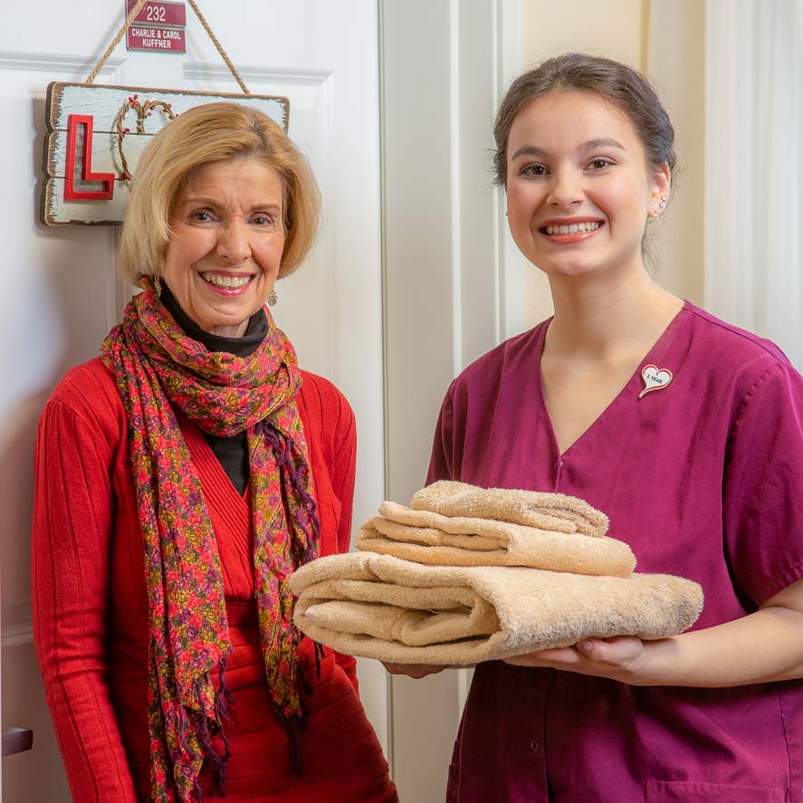 A team member delivering fresh linens to a resident at Ashton Gardens